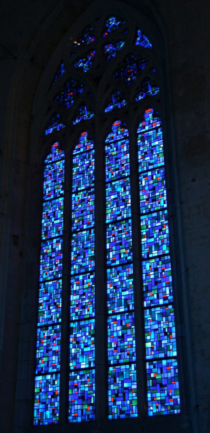Eglise abbatiale : vitrail réalisé en 1952 (baie sud) est composé de panneaux de verre aux motifs répétitifs mais agencés de différentes manières. Dans chacune des baies, une seule pièce est unique. - Saint-Amant-de-Boixe