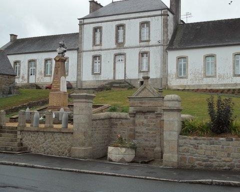 Le monument aux morts à coté d'une ancienne fontaine , derrière, l'école publique dont le  bâtiment central fut l'ancienne Mairie - Loguivy-Plougras