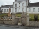 Photo suivante de Loguivy-Plougras le monument aux morts à coté d'une ancienne fontaine , derrière, l'école publique dont le  bâtiment central fut l'ancienne Mairie