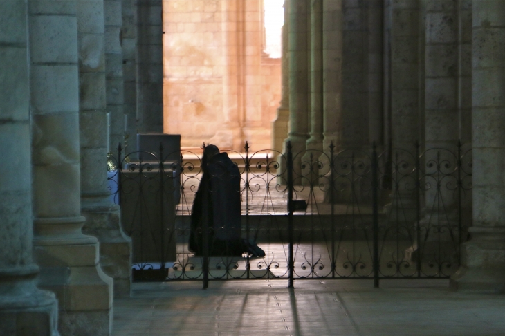 Moine en prière dans le collatéral de l'église Abbatiale. - Fontgombault