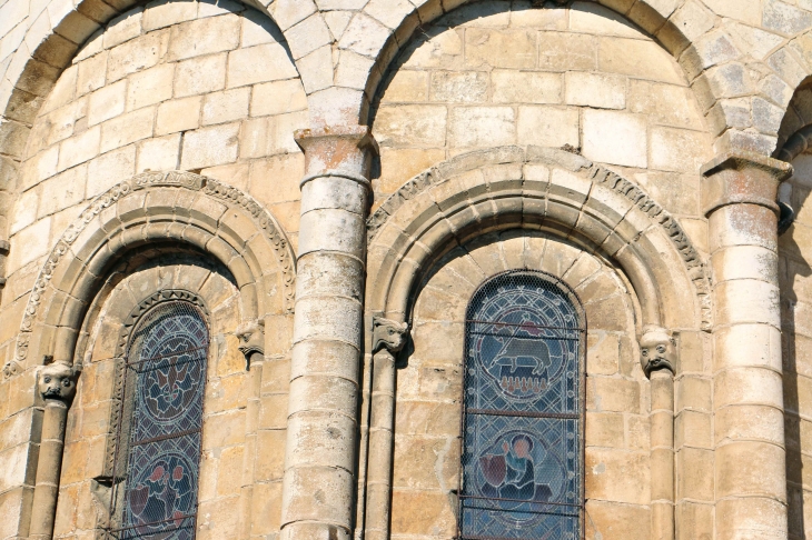 Détail du chevet, deux des trois fenêtres romanes du choeur, elles sont enjolivées par des têtes d'animaux fabuleux.  de l'église Saint Marcel. - Saint-Marcel