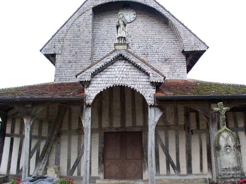 La façade Ouest de l'église, remarquez les écailles de bois qui recouvent tout le clocher au dessus du porche la statue de Saint Jaques. - Lentilles