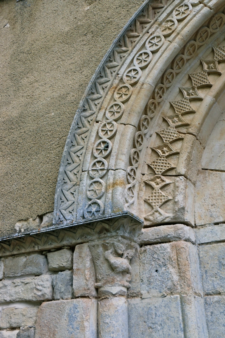 Détail : chapiteau, frise et archivolte scultés du portail de l'église du XIIe siècle. - Amuré